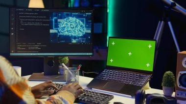 Terminal penceresinde programlama dili ile çalışan, bilgisayar ve yazma kodlarında izole edilmiş bir model kullanan Afrikalı Amerikalı web geliştirici. Siyah adam evden çalışıyor, yazılım sistemini izliyor. Kamera B.