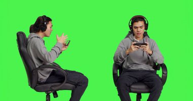 Asyalı oyuncular internetteki RPG yarışmasına cep telefonu oyunu oynayarak katılıyorlar, internet sunucusundaki diğer oyuncularla eğleniyorlar. Genç adam yeşil perde arkaplanına karşı oynanan oyun yarışmasının keyfini çıkarıyor.