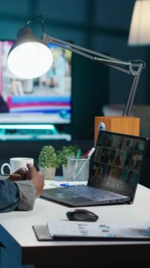 Daire ofisindeki iş görüşmesinde iş arkadaşlarını karşılayan dikey video uzaktan kumandalı işçi. Uzak video konferansına katılan serbest meslek sahibi bir kadın evdeyken tele-konferansa katılıyor.