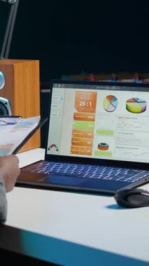 Evde çalışan dikey video muhasebecisi finansal belgeler hakkında notlar alıyor, iş geliştirme planı için satış raporlarını analiz ediyor. Proje için pazarlama istatistikleri kullanan uzak çalışan