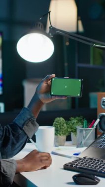 Dikey videolu kadın yeşil ekran akıllı telefonundaki videoları izlemek için borsayı kontrol etmeye ara veriyor. Krom anahtar telefon kullanarak evden çalışan hissedar pazar payı artışına bakıyor