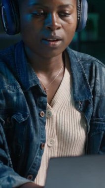 Dikey video çalışanı şirket projesi için verileri araştırırken müziğin keyfini çıkartıyor, bir gecede kişisel ev ofisinde görevler yapıyor. Dizüstü bilgisayarın önünde oturan ve kulaklık kullanan bir kadın.