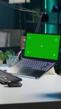 Dikey video Afrikalı Amerikalı kadın merkez ofise geliyor, masasına oturuyor, yeşil ekran dizüstü bilgisayar kullanıyor. Freelancer iş vardiyasına başlıyor, model defterini açıyor, e-posta iletişimi yapıyor