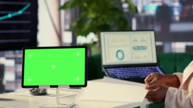 Siyahi hedef odaklı CEO tabletinde maket görüntüsüyle çalışıyor, veri analizi ya da gelir planlaması yapıyor. Başarı için ödeneği arttırmak amacıyla aylık gelir dengesi gözden geçiriliyor. Kamera A.