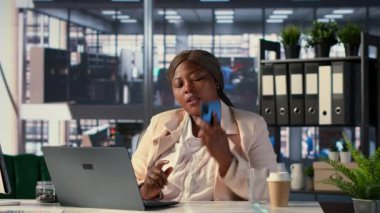 Afrikalı Amerikalı girişimci cep telefonuyla finansal planlama üzerinde çalışıyor, yatırımcıların görüşlerini ve verilerini paylaşmak için aramalarına cevap veriyor. Kadın CEO iş görüşmelerini telefonla yapıyor. Kamera A.