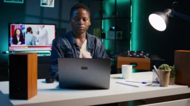 Oturma odasındaki kadın iş ortaklarından gelen e-postaları cevaplamak ve kahve içmek için dizüstü bilgisayar kullanıyor. Freelancer sıcak içecekten ve klavyede daktilo yazmaktan hoşlanıyor, kamera B