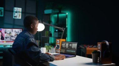 Uzaktan çalışan videograf, özel yazılım uygulamaları kullanarak video montajı yapıyor. Afrika kökenli Amerikalı video editörü dizüstü bilgisayardaki kurgu araçlarını kullanarak ofisteki film projesinin görüntülerini kesti, kamera B