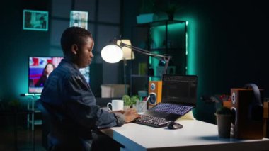 Yazılım geliştiricisi Java programlama dillerini kullanarak daire ofisindeyken laptop ekranına kod yazar. Programcı, evde çalışırken veritabanı hatalarını düzeltmeye çalışıyor, kamera B