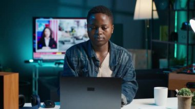 Freelancer müzik dinlerken takım projesi için kişisel ev ofisinde bilgisayar görevleri yapıyor. Uzaktan çalışan, gece geç saatlere kadar çalışan, dizüstü bilgisayarda yazan, kulaklık takan, kamera A