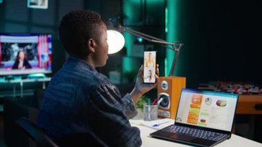 Ofiste çalışan bir kadın iş arkadaşlarıyla telekonferans toplantısı yapıyor. Akıllı telefon kullanıyor, beyin fırtınası yapıyor. Uzaktan çalışan iş arkadaşlarıyla çevrimiçi telefon görüşmeleri, araştırma analizi, kamera B