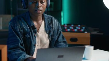 Teleworker şirket projesi için verileri araştırırken müziğin tadını çıkarıyor, bir gecede kişisel ev ofisinde görevler yapıyor. Dizüstü bilgisayarın önünde oturan ve kulaklık ve kamera A kullanan bir kadın.