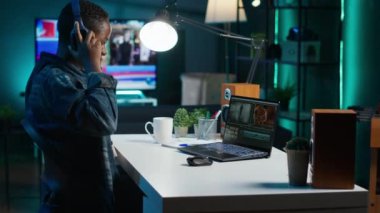 Video editörü ses efektleri ekliyor. Ev stüdyosunda çalışıyor. Ses kalitesini ölçmek ve geliştirmek için kulaklık kullanan kameraman, profesyonel yazılım ve kamera A ile klipleri düzenliyor