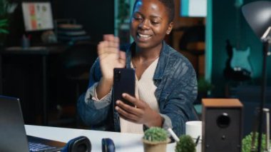 Telefon alan bir kadın, video konferans sırasında en iyi arkadaşıyla akıllı telefon kullanarak konuşuyor. El sallayan kişi, cep telefonundaki selam veren arkadaş evdeki video görüşme oturumu, kamera A