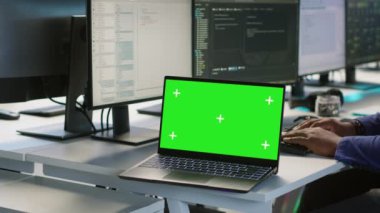 Çalışanlar, veri işleme gereksinimlerini optimize etmek için sunucu çiftliğinde çalışan yeşil ekran dizüstü bilgisayar kullanıyorlar. Masanın üzerindeki, veri merkezinde kodlama yapan işçilerin yanındaki, A kamerasının kapağını kapat.