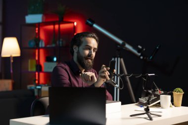 Neon lit stüdyosundaki medya yıldızı, markalı sponsorluk videosundan cep telefonunu sunuyor, özellikleri yakından analiz ediyor. Sosyal medya hesabı takip eden teknoloji meraklılarının telefonlarını inceleyen nüfuzlu kişi