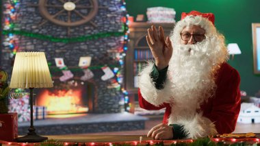 Noel Baba 'nın internetteki video konferansında çocuklarla konuşurken Noel arifesinde hediye dilekleri ararken el salladığı pov. Kırmızı takım elbiseli ve kışın beyaz sakallı Aziz Nick. Kamera A.