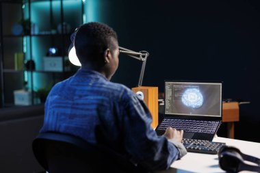 Afrikalı Amerikalı müteahhit yapay zekayla gelecekteki veritabanını yönetiyor. Siyahi kadın, programlama ve izleme ile siber güvenliği sağlarken dizüstü bilgisayarda çalışıyor..