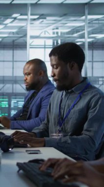 Dikey video Afrikalı Amerikan veri merkezi teknisyenleri yapay zeka öngörüsü bakım sistemleri uyguluyorlar. Sunucu merkezindeki kadın donanım arızalarını tespit etmek için yapay zeka kullanıyor. Kamera A.