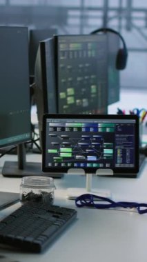 Boş veri merkezindeki dikey video elektronik cihazları donanım enerji tüketimini izliyor. Sunucu odasındaki ve el bilgisayarındaki potansiyel sistem hatalarını kontrol etmek için kullanılan masadaki bilgisayar monitörleri