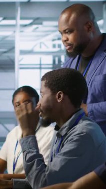 Dikey Veri Merkezi ekip lideri yapay zeka öngörü bakım sistemlerini uygulayan mühendisleri denetliyor. Sunucu çiftlik patronu donanımı tanımlamak için yapay zeka kullanan işçileri denetliyor