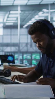 Sunucu odasındaki dikey video mühendisi belgeleri inceliyor, felaket kurtarma planları geliştiriyor ve en az dinlenme süresini sağlıyor. Veri merkezinde kağıt okuyan işçiler, analizleri kullanarak