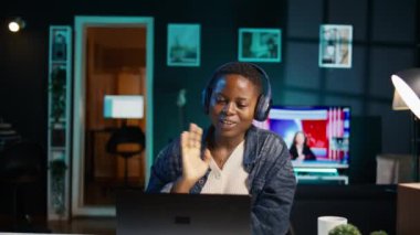 Neşeli kadın, dizüstü bilgisayarında kulaklık kullanarak televizyon izleyerek evde dinleniyor. Mutlu insan dairede boş vakit geçirmekten zevk alıyor, eğlence medyası içeriği tüketiyor, kamera B