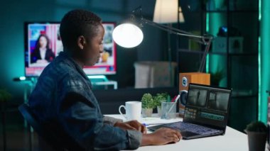 Uzaktan çalışan videograf, özel yazılım uygulamaları kullanarak video montajı yapıyor. Afrika kökenli Amerikalı video editörü dizüstü bilgisayardaki kurgu araçlarını kullanarak ofisteki film projesini, kamera A 'yı kesti.