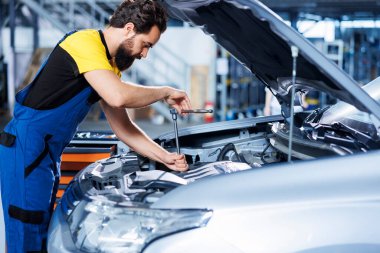 Mühendis gelişmiş mekanik araçlar kullanarak otomotiv performansını ve güvenliğini sağlayarak otomotiv motorunu ustalıkla inceliyor. Garaj çalışanı tork anahtarı kullanarak yıllık araç kontrolü yapıyor.