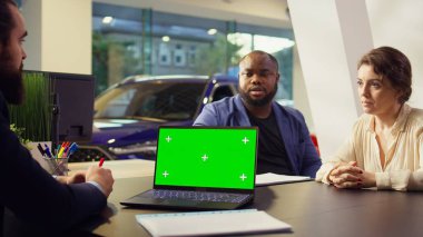 Galerideki müşteriler satın almak için yeni bir araç arıyorlar, satış elemanları tarafından sunulan seçenekler sunuluyor. Temsilci, müşterilerin arabaları, kamera B 'yi değerlendirmelerine yardımcı olmak için yeşil ekran defteri kullanıyor