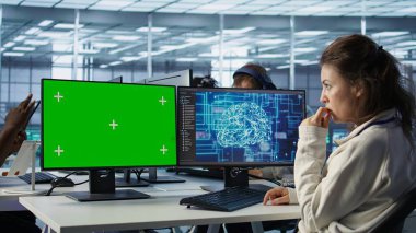 Sunucu merkezindeki yeşil ekran bilgisayar üzerinde çalışan bir çalışan veri işlemek için yapay zekayı kullanıyor. Yapay zeka kullanarak ağ kaynaklarını kontrol eden sunucuları güncelleyen Chroma Key PC 'deki IT geliştiricisi, kamera B