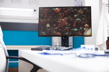 Sağlık hizmetleri teknolojisinin altını çizen virüs hücrelerini gösteren boş bir masa ve masaüstü bilgisayar ekranı olan doktorların ofisi. Boş tıbbi odadaki modern klavye ve bilgisayar dijital biyolojiye odaklanıyor.