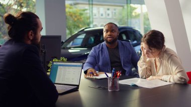 Müşteriler, galeride doğru aracı bulduktan ve satın almaya karar verdikten sonra doğru fiyat ve finansman seçenekleri üzerinde pazarlık ediyorlar. Kontrat şartlarını ve koşullarını okuyan bayi müşterileri, kamera B