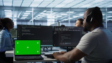 Kulaklıkla müzik dinlerken sunucu çiftliğinde programcının yanındaki izole ekran bilgisayarı. İşçi krom anahtar defteri, kamera B 'ye izinsiz erişime karşı donanımı koruyor