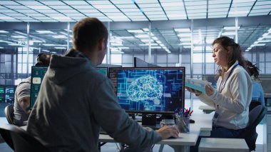 Yönetici ofisinde teftiş yapıyor, BT çalışanı tarafından yapay zeka difüzyon uygulaması oluşturulup yapılmadığını kontrol ediyor. Takım lideri denetleme mühendisi yazılım üreten yapay zeka üreten videolar, kamera B