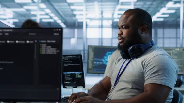 Yüksek teknoloji firmasında çalışan bir mühendis farklı iş yükleri için bilgisayar kaynakları sağlıyor. Veri merkezi süperbilgisayarlarını, kamera A 'yı izlemekle görevli Afrikalı Amerikalı bir adam.