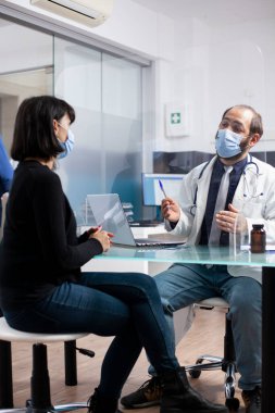 Sıhhiye uzmanı kadın hastalarla oturup sağlık sorunlarını tartışıyor ve hastane ofisindeki dizüstü bilgisayardaki notları inceliyor. Beyaz kadın için sağlık tedavi planlarını tanımlayan genç bir erkek doktor.