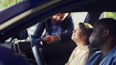 Showroom satıcısı müşterileri ikna etmek için test sürüşünü bitirdikten sonra tabletlerinde istatistik çizelgeleri gösteriyor. Galeri acentesi, araç sürme ölçüm grafiklerini çift olarak gösteriyor, kamera B