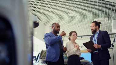 Araba galerisi satıcısı, müşterileri araç yeteneklerini göstermek için test sürüşlerine davet ediyor. Showroom temsilcisi müşterilerin satın almak için isteğe bağlı ekipman öneriyor, kamera B