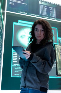 Kadın hacker gelişmiş tekniklerle ağ güvenliğini aşıyor, siber savunma iş başında. Bilgi işlem uzmanı büyük ekranda önemli bir melez savaş istihbaratını inceliyor..