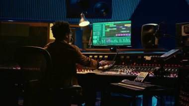 İzleme mühendisi yeni bir albüm üzerinde çalışıyor ve hit şarkı kaydediyor, hareket eden faders ve renkli sayaçlarla karıştırma konsolunu idare ediyor. Sürgüleri ve kolları iten yetenekli bir ses tasarımcısı. Kamera B.