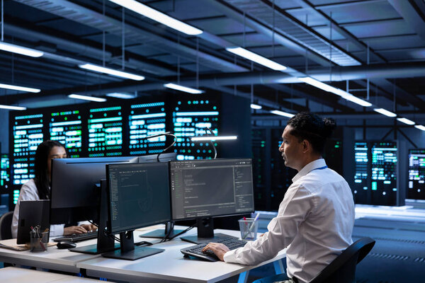 Engineering coworkers in data center looking for firewall misconfigurations affecting servers. IT staff members in server room check systems bottlenecks leading to sluggish data transfer rates