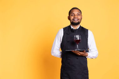 Waiter offering a glass of wine to customers waiting for their food at the table, providing excellent service at a restaurant. Professional staff with uniform bringing drinks to clients. clipart