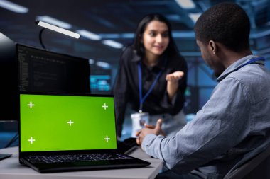 Bulanık arkaplanda veri işleme için sunucu merkezini optimize eden ekip tarafından kullanılan izole ekran laptopuna odaklan. Veri merkezini denetleyen işçilerin kullandığı krom anahtar defterini kapat