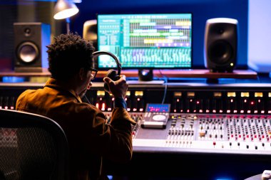 Ses uzmanı mikser kontrol panelinde ses seviyelendiriyor. Profesyonel müzik stüdyosu konsepti. Yetenekli bir müzik teknisyeni sesi açar ve bir karıştırma konsoluna efekt ekler ekler, canlı şarkılar kaydeder.