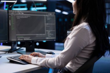 Veri merkezindeki yazılım geliştiricisinin klavyede yazarken, donanım üzerinde kontrol yapmak için bilgisayarda çalışırken yakın plan görüntüsü. Bakım bittikten sonra sunucu merkezine veri girişi yapan kadın