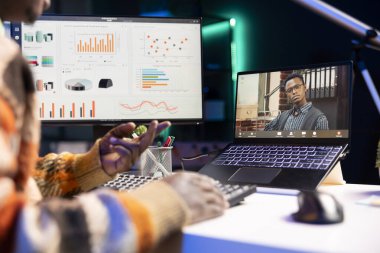 Afrikalı Amerikalı serbest çalışan erkek müşterilerle bilgisayar başında sanal görüşme görüşmelerine katılıyor, evde çalışıyor ve gelir istatistikleri hakkında görüşlerini paylaşıyor. Ekrana bakan ve video çağrısını dinleyen kişi.