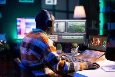 Videograf uzmanı evinde bilgisayardaki video klipleri ayarlıyor, renk tekeriyle çalışıyor ve görsel efektler ekliyor. Afrikalı Amerikalı editör video sonrası prodüksiyon için fx montaj yapıyor.