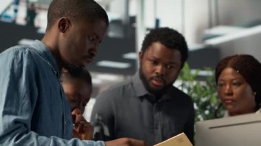 Afrikalı Amerikalı ekip, gelecekte şirket büyümesi için bilgilendirilmiş kararlar almak üzere takım çalışması ve veri analizini vurgulayarak bir iş alanında finansal planlama projesi üzerinde işbirliği yapmaktadır. Kamera A.