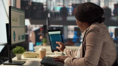 Ofis masasındaki kendine güvenen iş kadını rapor yazma ve cevap verme, idari işler yönetimi üzerinde çalışıyor. Siyahi kadın uzmanlar başarıyı garanti altına almak için hedeflerini gözden geçiriyorlar. Kamera A.