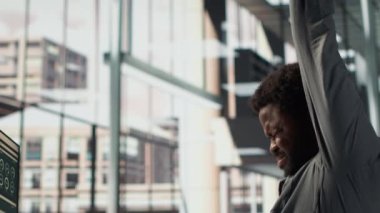 Siyahi erkek CEO sırt ağrısıyla uğraşıyor ve kaslarını masada geriyor, yanlış bir duruşla oturuyor ve düzeltmeye çalışıyor. Genel müdür veri analiziyle çalışıyor. Kamera A.